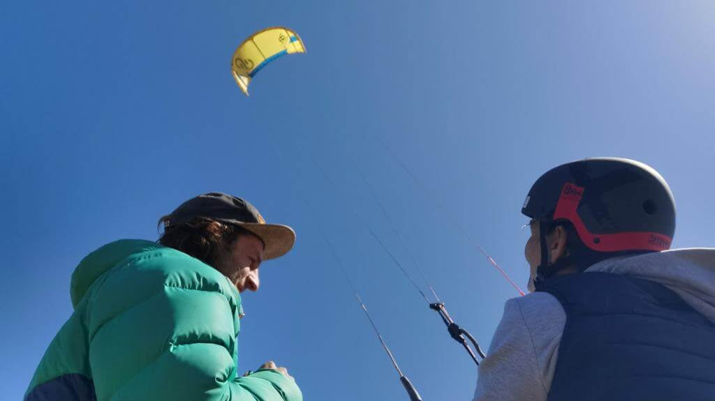 The Guide To Kitesurfing Lessons North West England featuring two surfers with a kite in the sky.