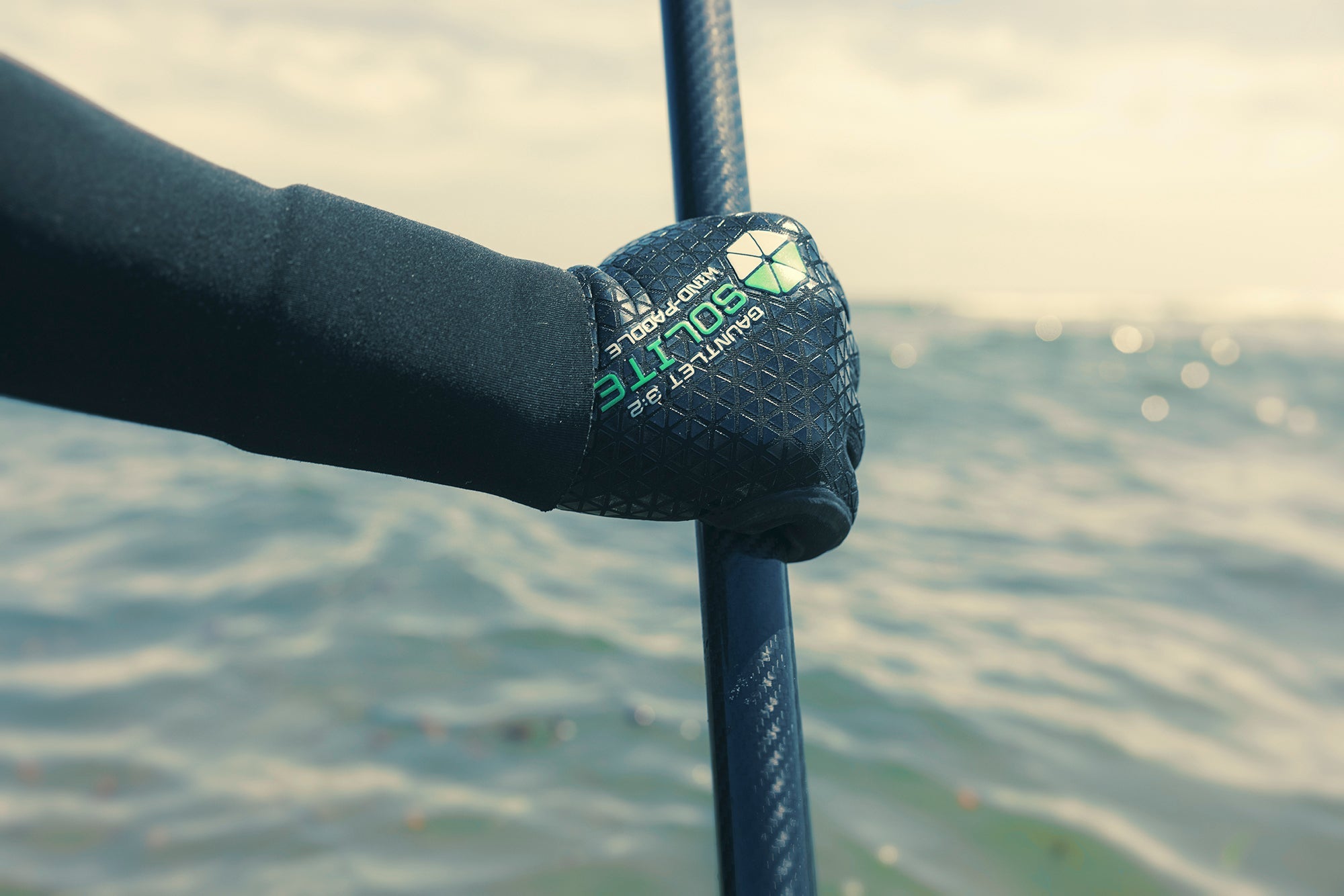 Person wearing 3:2 Wind/Paddle Gauntlet Wetsuit Gloves while gripping a paddle in water.