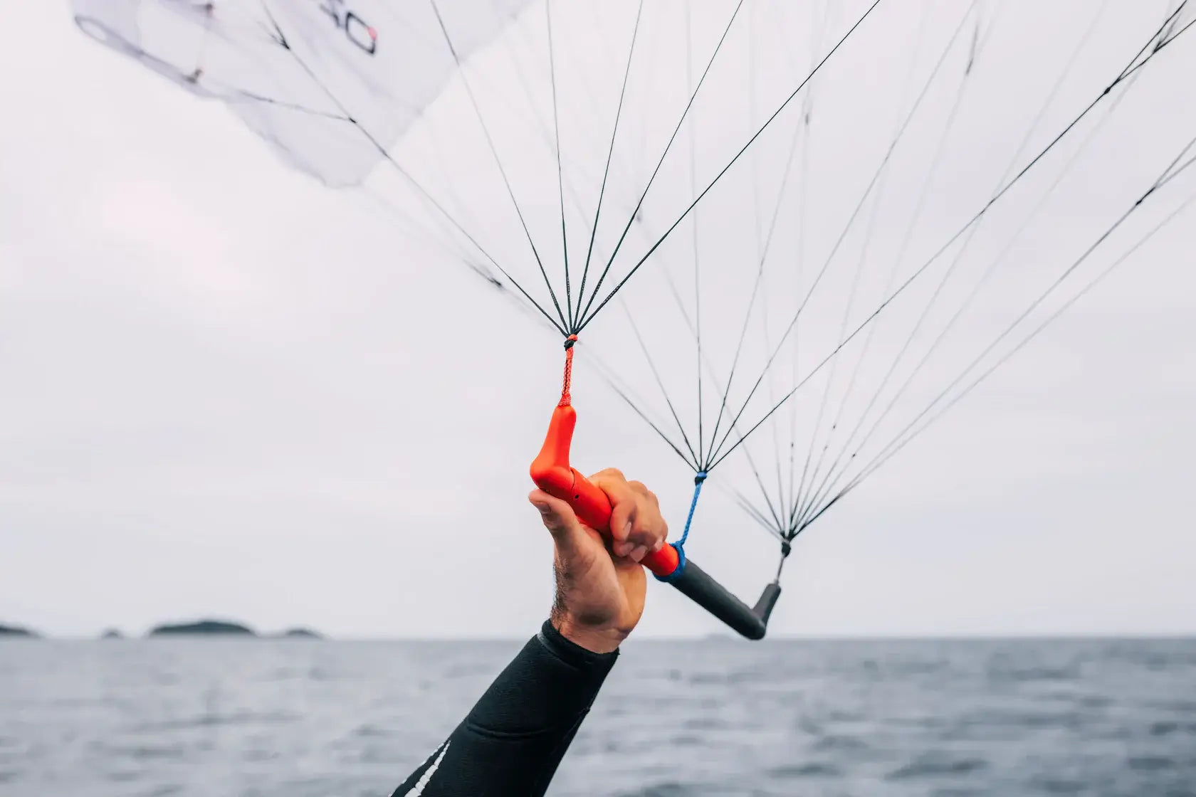 Ozone Pocket Rocket V1 – Parawing Foiling Freedom showcased with a hand gripping the control lines on a windy day.