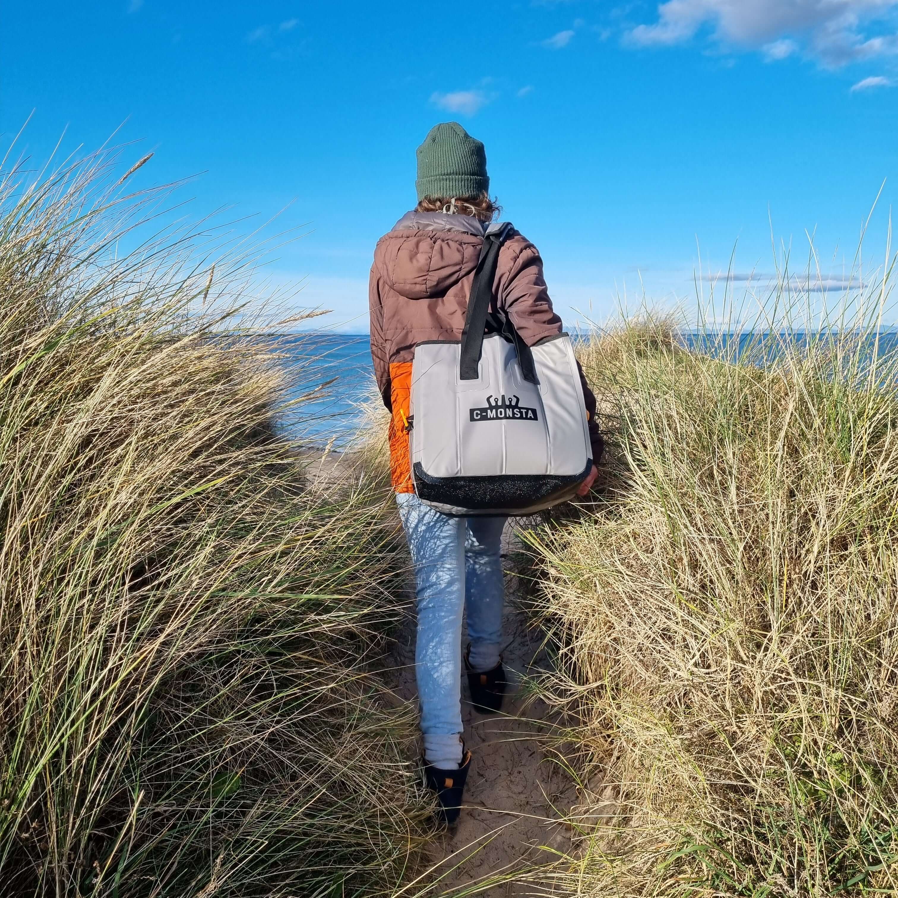 C-Monsta Mini Split Bag | Compact Wet & Dry Gear Bag carried along a sandy path by the water.