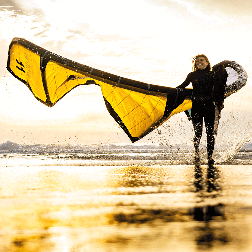 How to Use a Trainer Kite Safely (and Effectively): person flying a yellow trainer kite at the beach