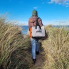 C-Monsta Mini Split Bag | Compact Wet & Dry Gear Bag carried along a sandy path by the water.