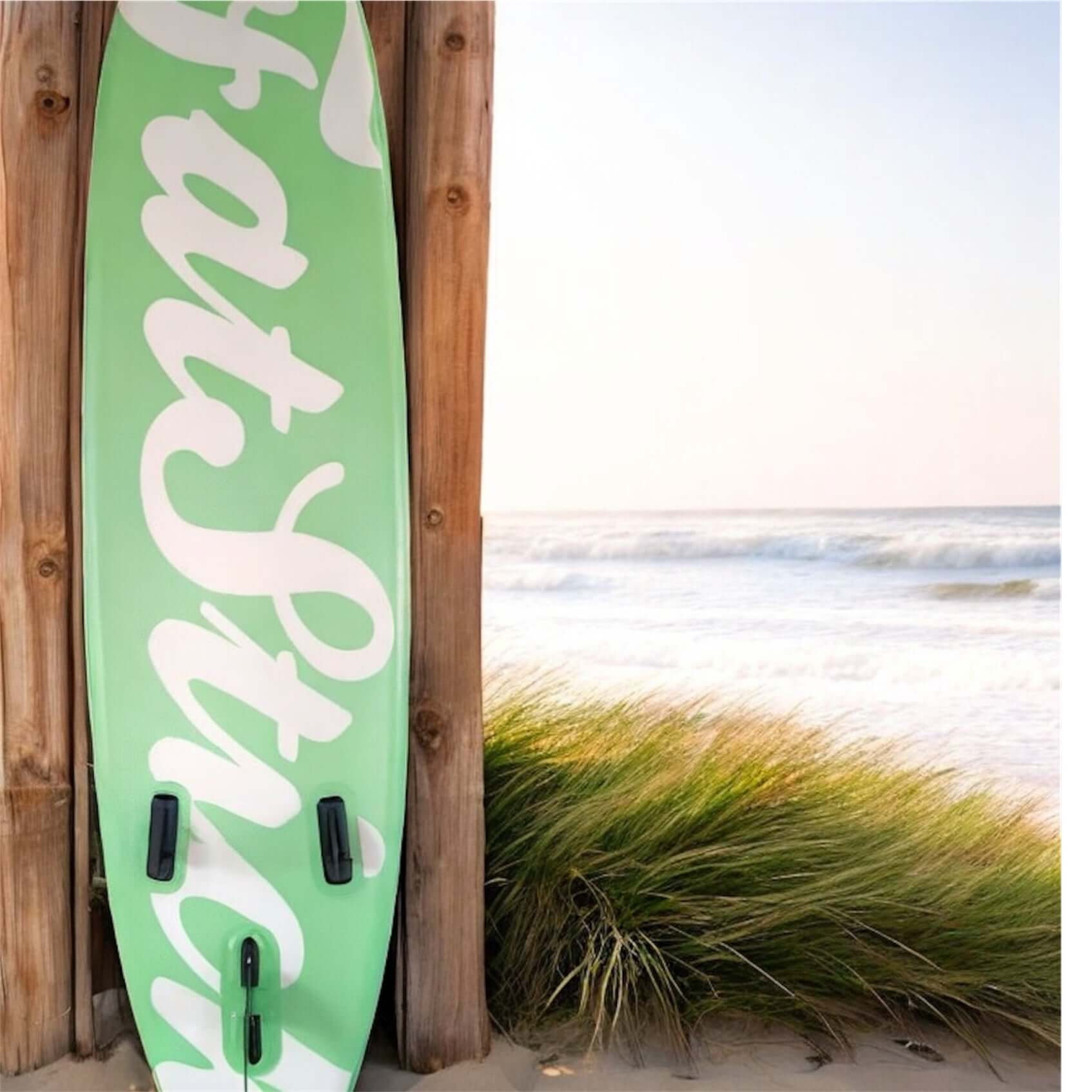 Fatstick AirStick 10'6 Inflatable SUP Package 2026 leaning against wooden wall by the beach.