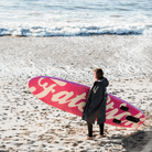 Person standing on beach with Fatstick AirStick 10'6 Inflatable SUP Package 2026, facing the ocean waves.