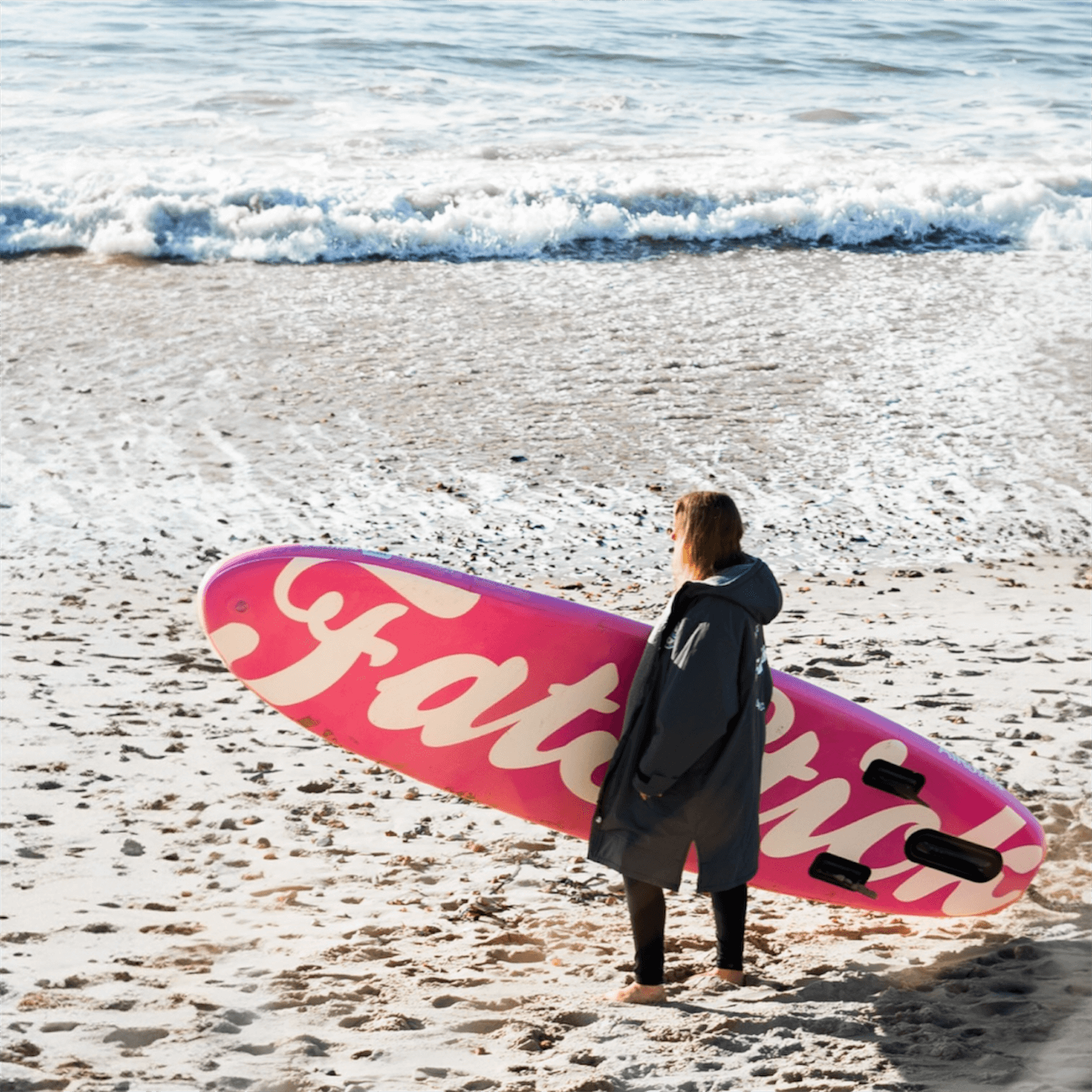 Person standing on beach with Fatstick AirStick 10'6 Inflatable SUP Package 2026, facing the ocean waves.