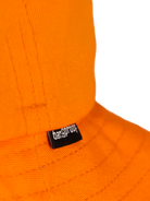 Close-up of an orange hat featuring Bangproof brand tag, showcasing vibrant color and quality craftsmanship.