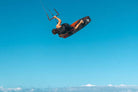 Ozone Code V5 Kiteboard – Freeride Performance Twintip in action with a rider jumping against a clear blue sky.