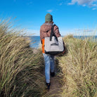 C-Monsta Mini Split Bag | Compact Wet & Dry Gear Bag carried along a sandy path by the water.
