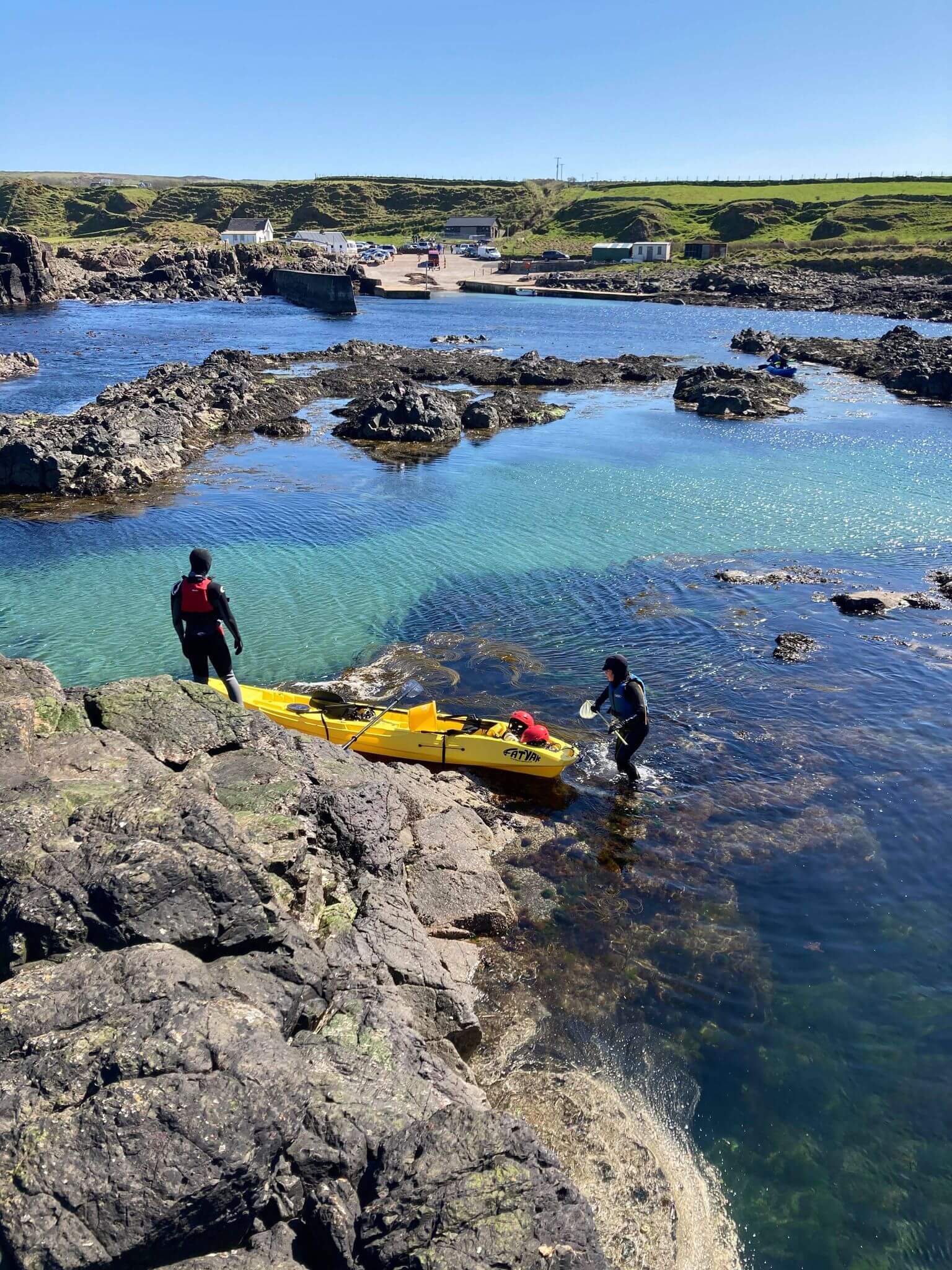 MAHEE Double Seater Kayak Yellow Package Deal 🟡 being launched in a serene rocky waterway.