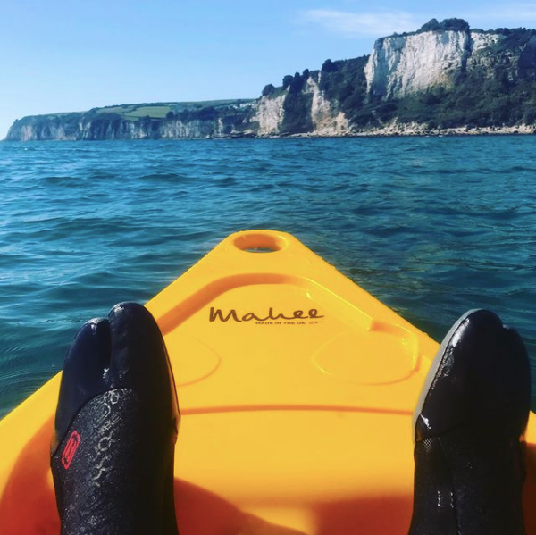 Mahee Tandem Kayak | Plastic Neutral | Yellow | Stable & Durable with feet paddling in water near cliffs.